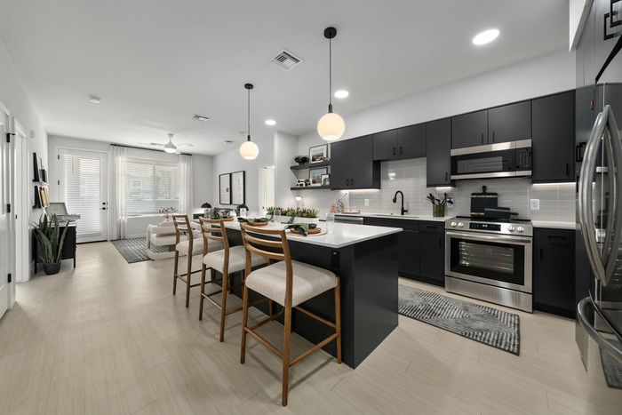 Navona kitchen, cabinet space, stainless steel appliances, ceiling lighting, facing living room