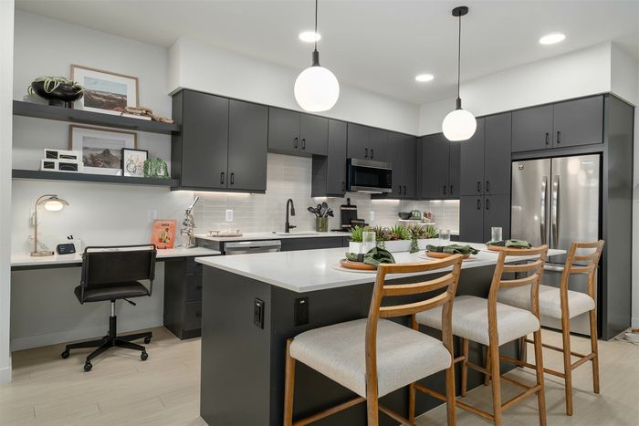 Navona kitchen, cabinet space, stainless steel appliances, ceiling lighting, island with bar stool chairs