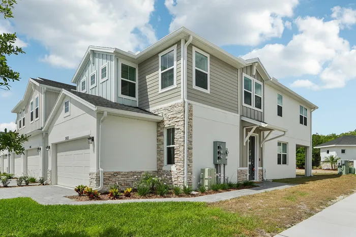 The exterior of the Alexander Park townhomes in Kissimmee, FL, featuring lawns and attached garages.