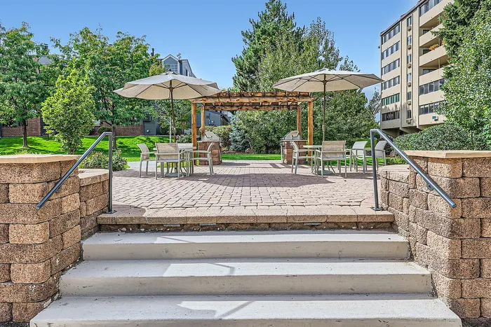 Inviting patio area with tables, chairs, and umbrellas surrounded by lush greenery.