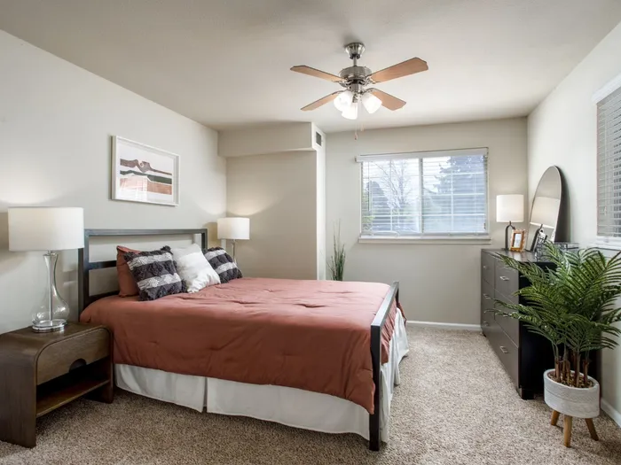 Inviting bedroom with a red comforter, natural light, and stylish decor.