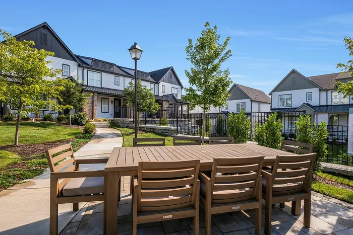 Charming residential community showcasing modern townhouses with beautifully landscaped yards and elegant outdoor dining area.