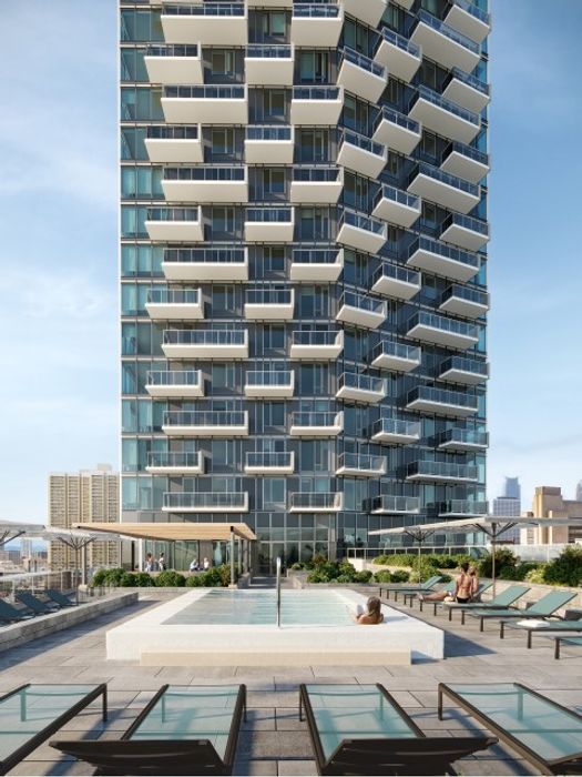 Modern high-rise building with a unique geometric balcony design, set against a clear blue sky with city views in the background.