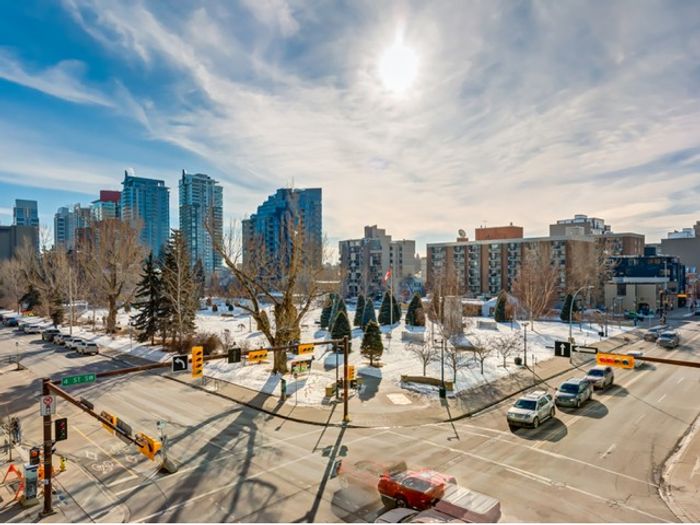 Panoramic view of the Denver skyline from One Park, featuring snowy park grounds, modern high-rise buildings, and a clear sunny sky.
