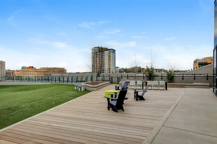 Contemporary rooftop terrace with stylish deck chairs, lush green space, and panoramic city views.