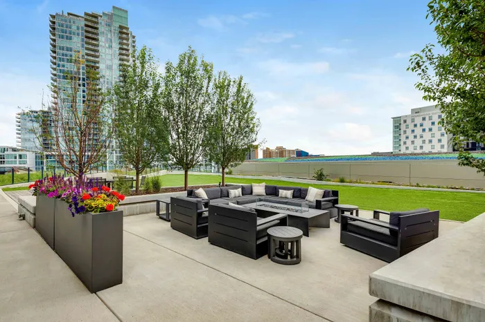 Luxurious outdoor patio with modern seating, vibrant flower arrangements, and urban skyline view.