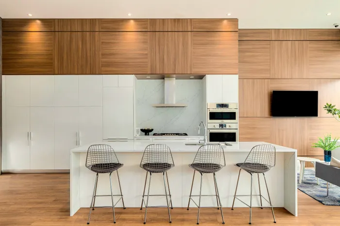 Contemporary kitchen with sleek wood paneling, island seating, and modern appliances, perfect for stylish home entertaining.