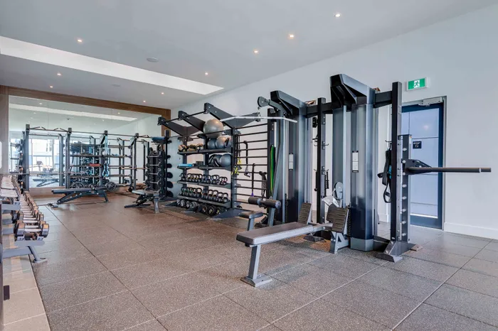 Modern fitness center featuring state-of-the-art gym equipment, weight racks, and exercise benches in a bright, spacious setting.