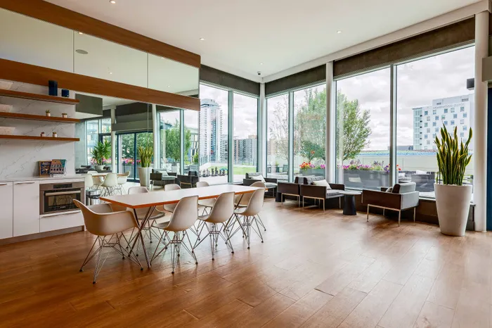 Modern communal area with sleek dining set, large windows, and lush greenery, offering an inviting and open atmosphere.