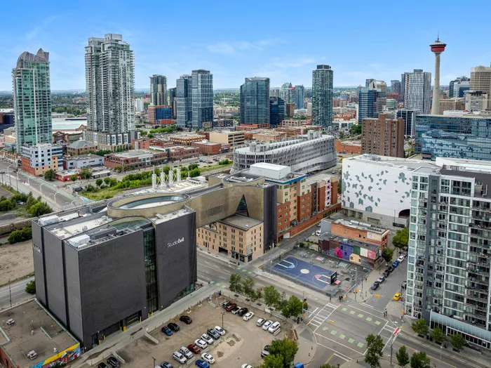 Vibrant urban skyline showcasing modern skyscrapers, lush greenery, and a colorful basketball court in a lively cityscape.