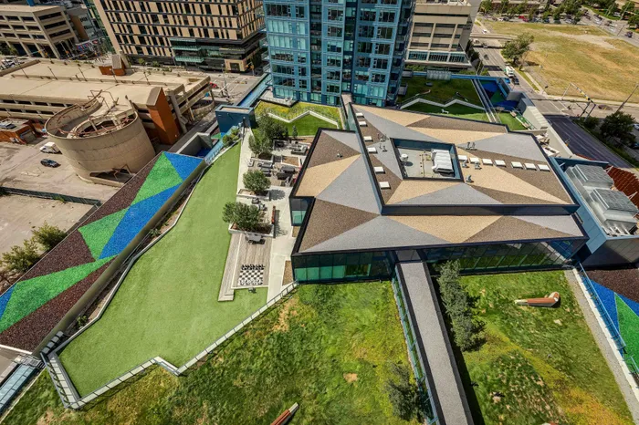 Magnificent rooftop view with lush green spaces, modern geometric architectural design, and vibrant mosaic accents.