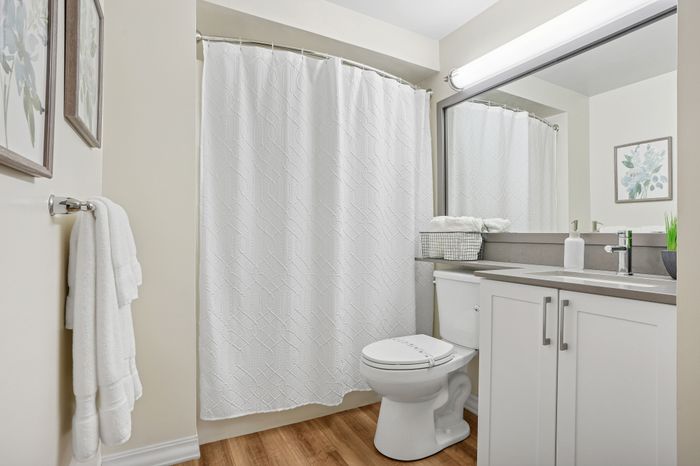 Elegant bathroom with modern fixtures, featuring a chic white shower curtain, plush towels, and a stylish vanity with ample storage.