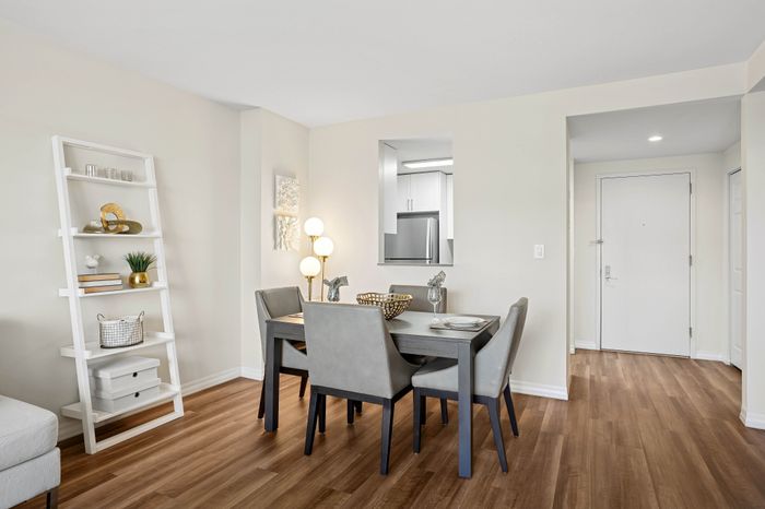 Bright and modern dining area with elegant table, chic decor, and warm hardwood floors, leading into a sleek kitchen.