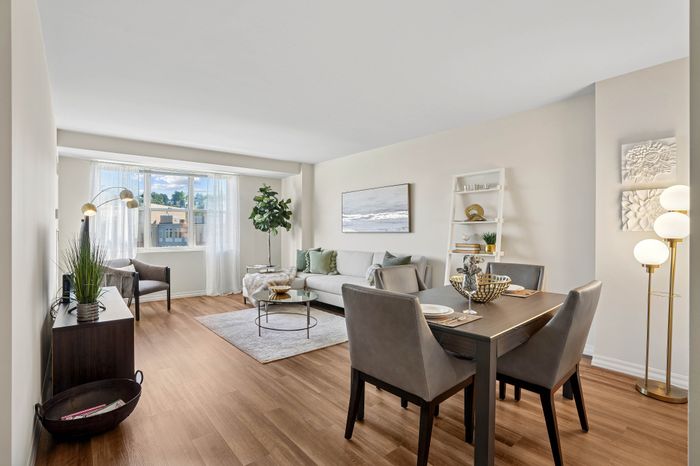 Bright and inviting living room with modern decor, featuring a plush sofa, elegant dining area, and large window with sheer curtains for natural light.