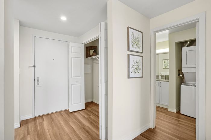 Inviting apartment entrance with chic hardwood floors, elegant decor, and a convenient in-unit laundry room.