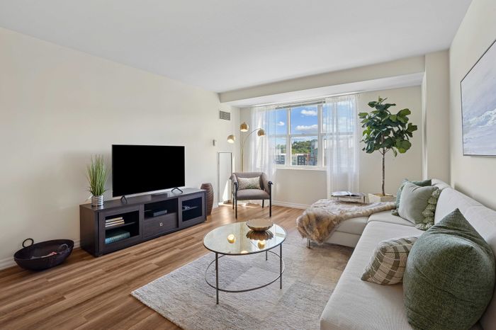 Modern and inviting living room with natural light, featuring a cozy white sectional sofa, stylish coffee table, and entertainment center.