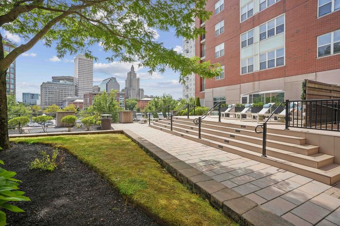 Charming outdoor patio of a modern apartment building with scenic city skyline views and comfortable lounge chairs.