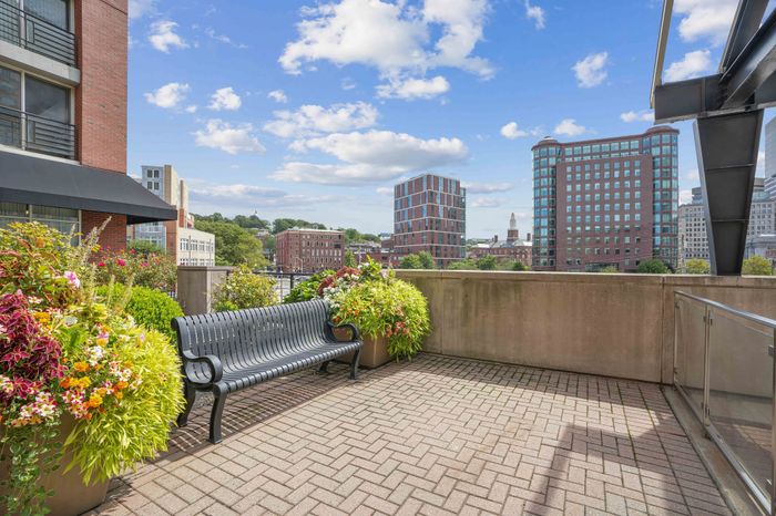 Charming urban terrace with vibrant planters and a sleek bench overlooking a stunning city skyline.