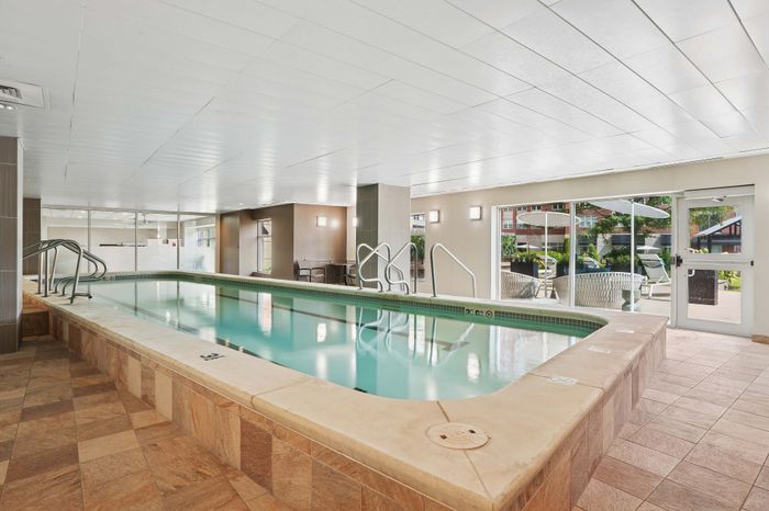 Luxurious indoor pool area with elegant tile flooring and bright natural light, perfect for relaxation and leisure.