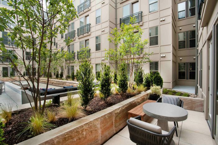 Chic urban courtyard with lush greenery, modern outdoor seating, and stylish architecture, perfect for relaxation and gatherings.