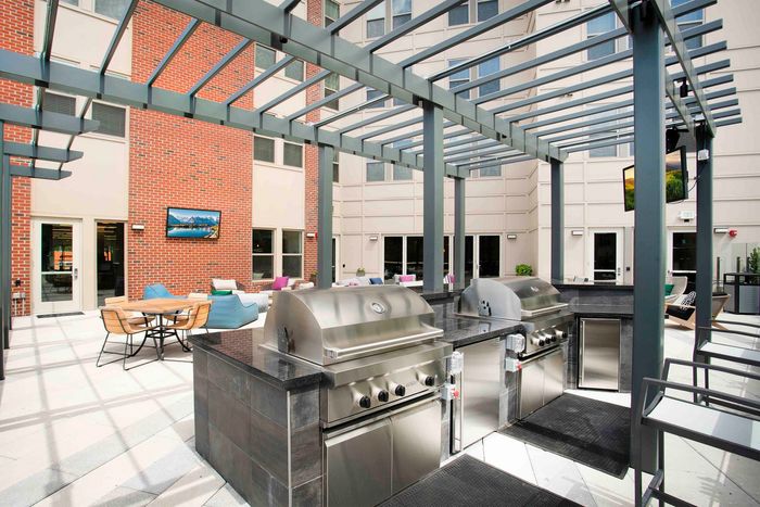 Chic outdoor patio boasting modern stainless steel grills, stylish lounge seating, and a vibrant atmosphere perfect for entertaining.