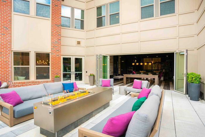 Luxurious outdoor patio featuring modern fire pit, vibrant seating with colorful cushions, and expansive open-air dining area.