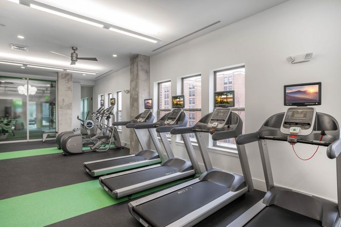 Modern on-site gym with state-of-the-art treadmills and exercise bikes, flooded with natural light for an energizing workout experience.