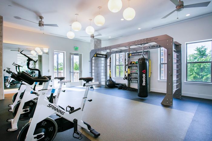 Bright and modern fitness center featuring state-of-the-art spinning bikes and a versatile workout station for an invigorating exercise experience.