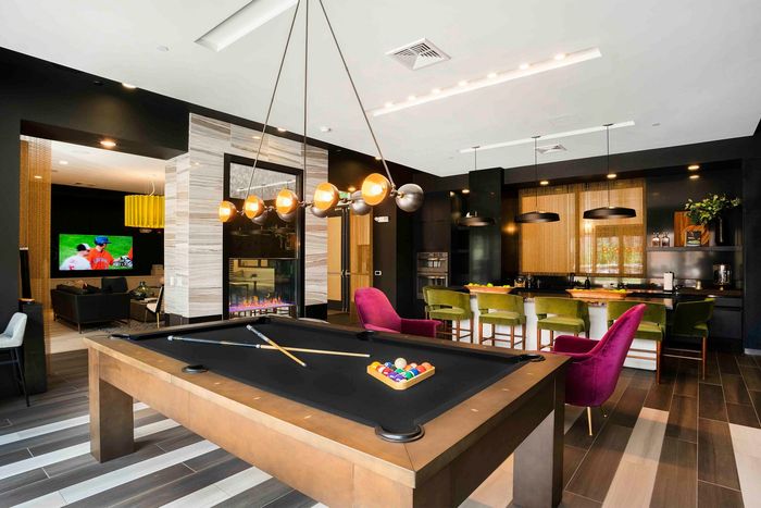 Luxurious modern lounge with a stylish billiards table, vibrant seating, and a sleek kitchen area perfect for entertaining.