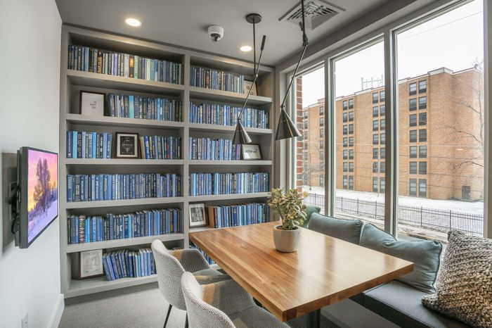 Modern reading nook with elegant bookshelves, cozy seating by large windows, and ambient lighting ideal for relaxation.