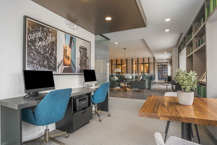 Contemporary co-working space featuring modern computers, vibrant decor, cozy seating, and abundant natural light, ideal for productivity and relaxation.