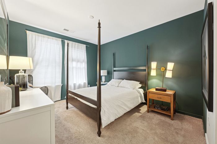 Inviting bedroom with a chic four-poster bed, elegant green walls, and soft natural lighting.