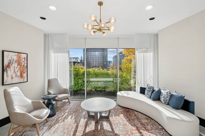 Elegant modern living room with floor-to-ceiling windows, contemporary seating, and garden views in a luxurious apartment.