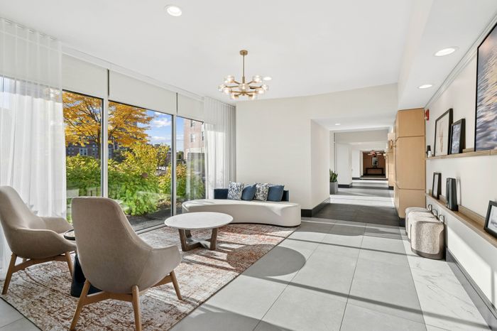 Elegant lobby area featuring chic seating, large windows with lush garden views, and modern decor.
