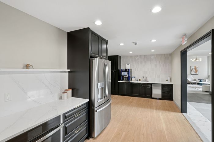 Sleek modern kitchen featuring elegant black cabinetry, stainless steel appliances, and a bright open space design.