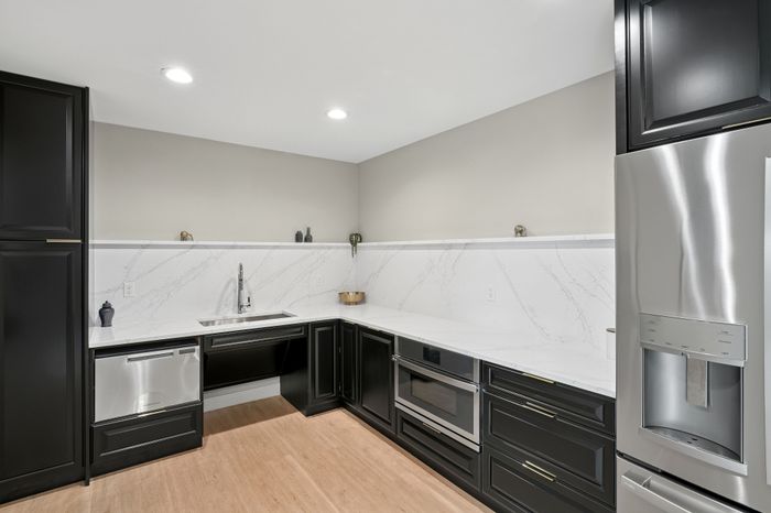 Modern kitchen featuring sleek black cabinets, elegant marble countertops, and high-end stainless steel appliances.
