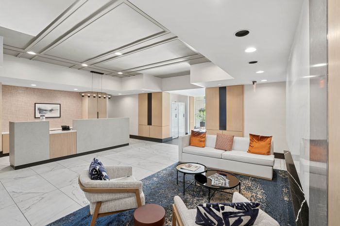 Elegant apartment lobby featuring modern marble flooring, a chic reception desk, and a cozy seating area with stylish decor.