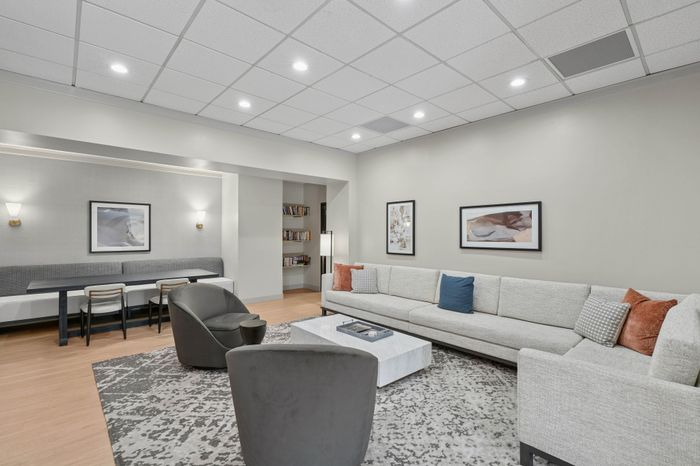 Elegant living space with modern gray sofa, chic coffee table, contemporary artwork, and a cozy reading nook.