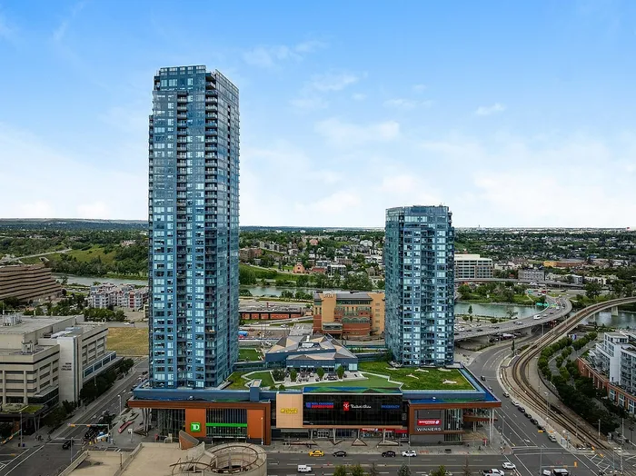 Majestic cityscape view featuring modern high-rise buildings with lush greenery and a vibrant shopping center below.