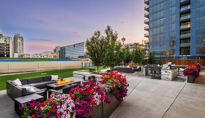 Luxury urban apartment terrace featuring modern seating, vibrant flower arrangements, and ambient evening lighting against a stunning cityscape backdrop.