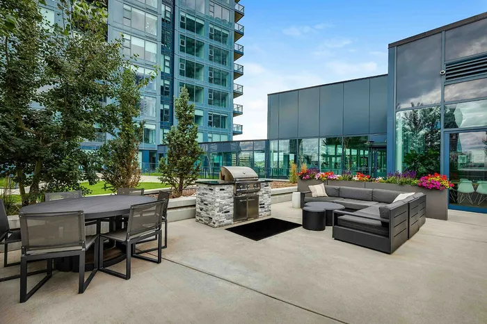 Luxurious rooftop patio with modern seating, vibrant flower arrangements, and a sleek barbecue station, offering exquisite urban living.