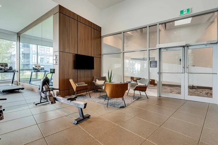 Modern gym with sleek exercise equipment, elegant seating area, and large windows providing natural light.