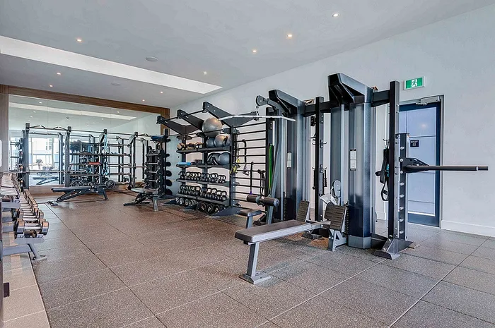 Modern gym with state-of-the-art fitness equipment, free weights, and exercise benches in a bright, spacious setting.