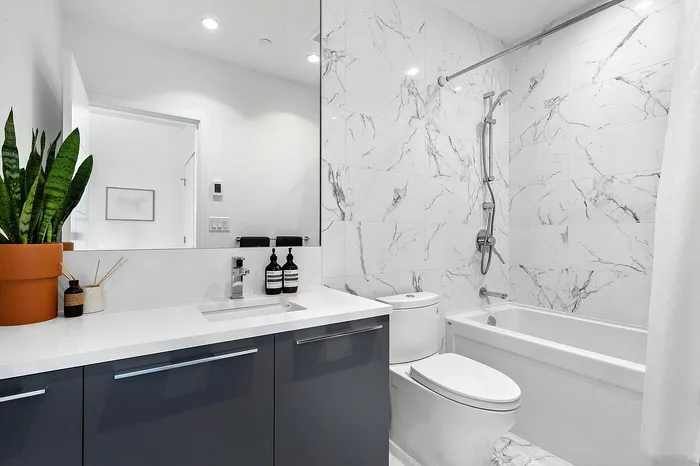 Elegant bathroom with marble tiles, modern vanity, and sleek chrome fixtures, offering a luxurious and inviting space.