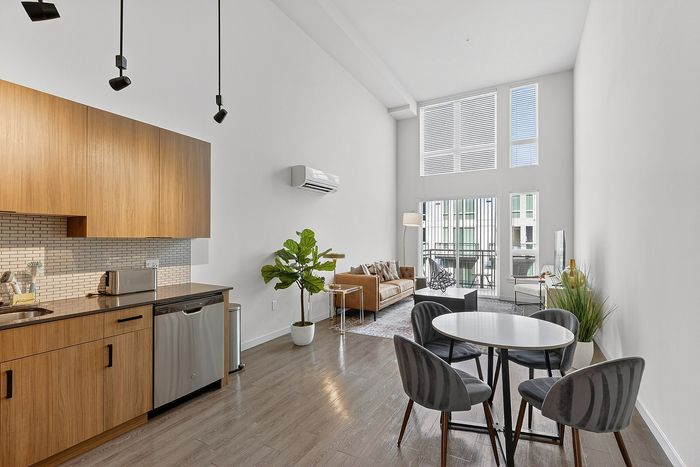 Contemporary open-plan living room with natural light, wood accents, and modern kitchen; perfect for stylish urban living.