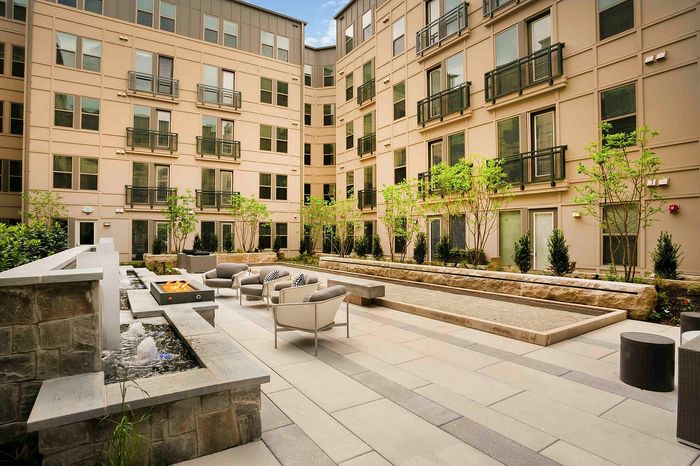 Modern apartment courtyard featuring elegant outdoor seating and lush greenery, ideal for relaxing and social gatherings.