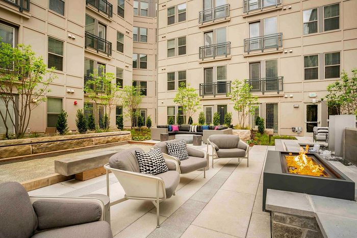Chic apartment courtyard featuring stylish outdoor seating, vibrant greenery, and a modern fire pit for a luxurious urban retreat.