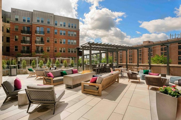 Stunning pool deck with stylish seating, vibrant cushions, and modern pergolas overlooking a scenic urban skyline.