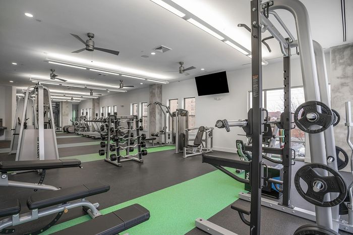 Modern, well-equipped gym featuring state-of-the-art fitness equipment, bright lighting, and spacious workout areas.