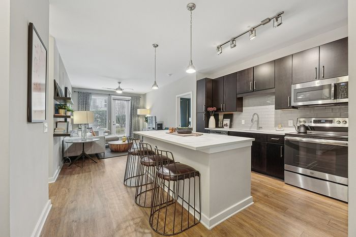 Modern open-concept kitchen and living area with sleek dark cabinetry, stylish island seating, and inviting natural light.